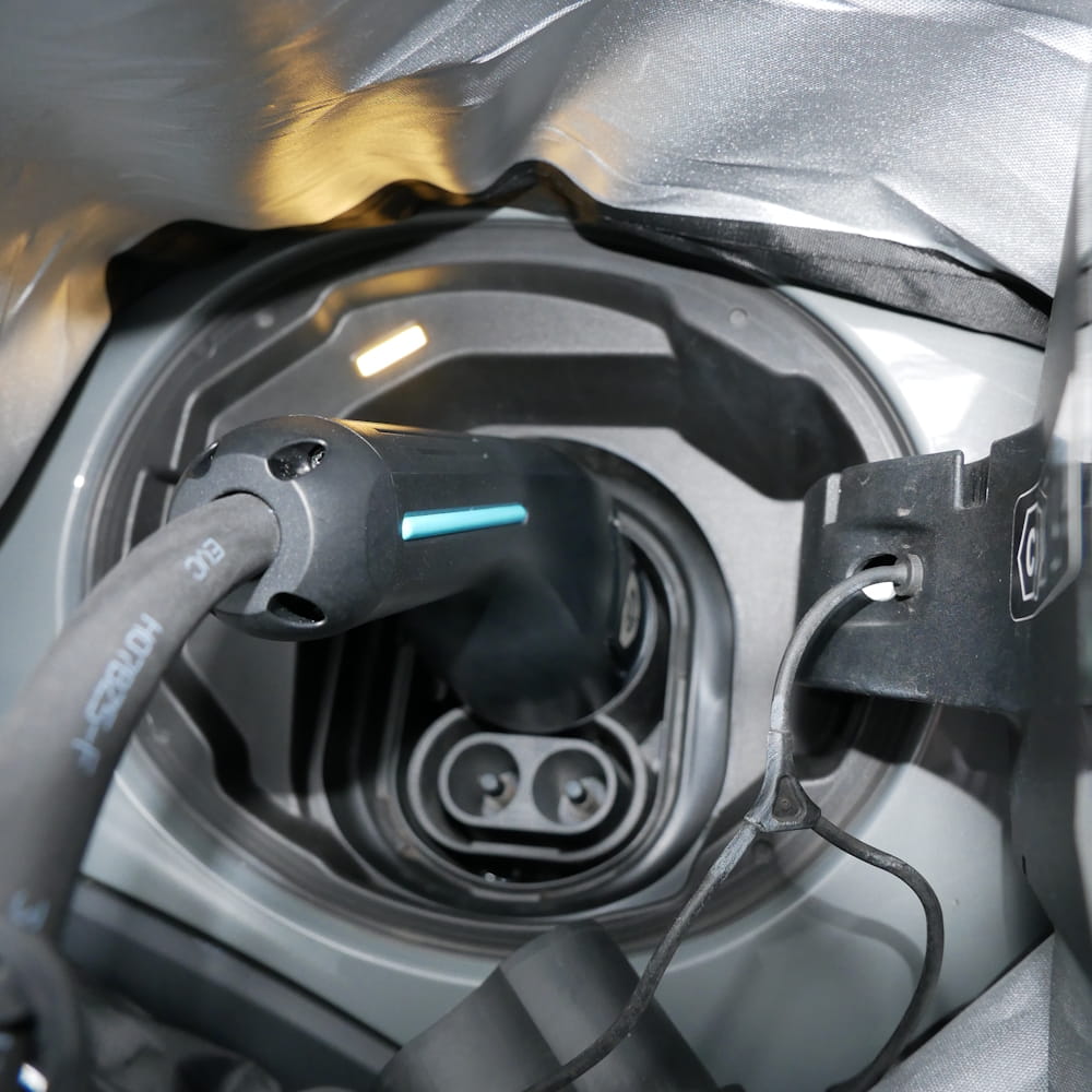 A unique perspective sot, showing an electric car's charge port from inside the magnetic EV charge port cover